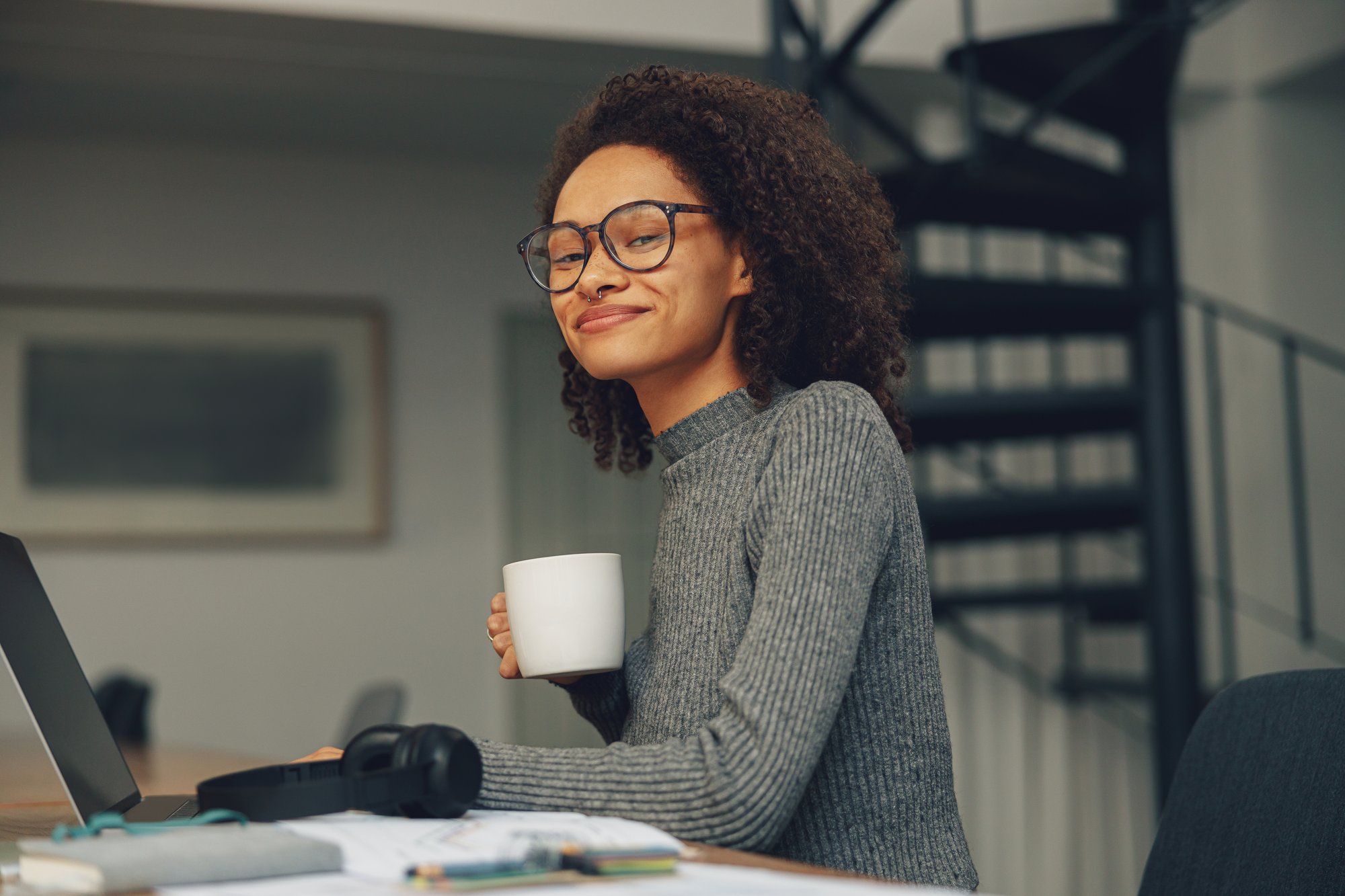 young-woman-freelancer-working-laptop-modern-coworking-while-standing-near-window